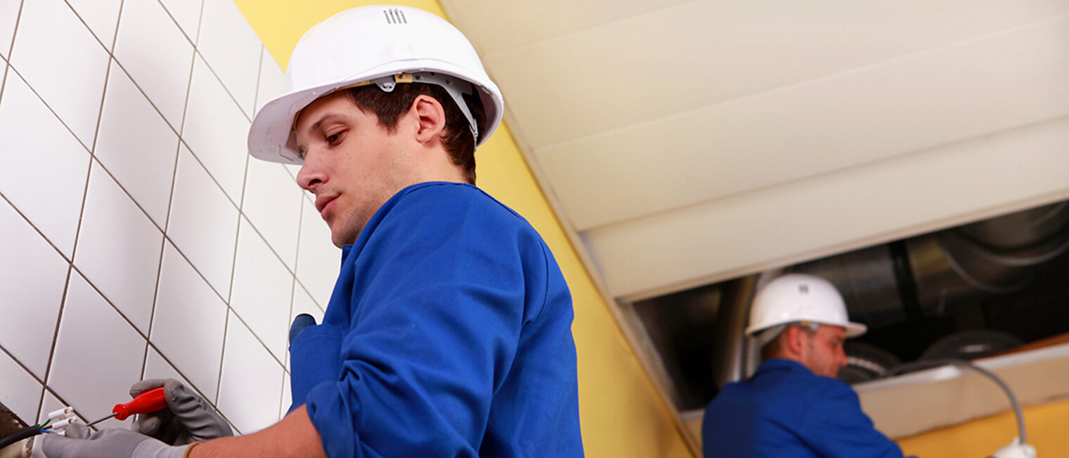 Zwei Elektrotechniker arbeiten an Stromkabeln im Sanitärbereich Zwei Elektrotechniker arbeiten an Stromkabeln im Sanitärbereich