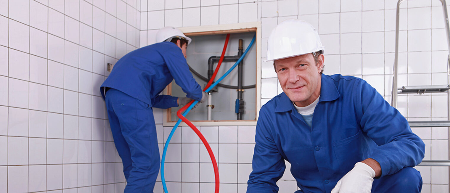 Zwei Heizungsbauer bei der Arbeit im Bad Zwei Heizungsbauer bei der Arbeit im Bad